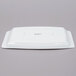 A white rectangular Arcoroc tray with a logo on a gray surface.