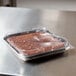 A brownie in a Solut clear plastic container with a square low dome lid on a table.