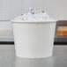 A white Lavex disposable paper ice bucket filled with ice on a counter.