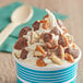 A cup of ice cream with TWIX® toppings including caramel and chocolate chips.