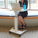 A woman using a Luxor pneumatic adjustable height lectern as a desk in a corporate office.
