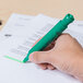 A hand holding a Universal fluorescent green desk style highlighter over a piece of paper.