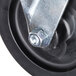 A close-up of a black metal caster wheel with a metal plate and nut.