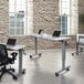 A Luxor adjustable height flip top nesting table with laptops on it in a room with desks and chairs.