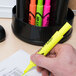 A person's hand using an Avery yellow desk style highlighter on paper.