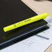 A Universal yellow chisel tip pocket highlighter on a black notebook.