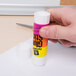 A hand holding a white Avery Glue Stic.
