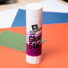 A white and purple Avery glue stick tube on a table.