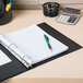 An Avery black economy non-view binder on a desk with a pen and calculator.