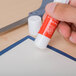 A hand using a Universal clear glue stick to make a paper.