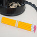 A beige rubber band wrapped around a bunch of yellow pencils on a desk.