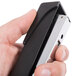 A hand using a black and silver Universal Classic stapler.