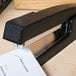 A Universal black classic full strip desktop stapler on a piece of paper.