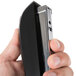 A hand holding a black Universal Executive desktop stapler.