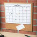 A Universal cork tile panel with a calendar on it.
