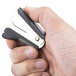 A hand holding a black and silver Universal Jaw Style Staple Remover.