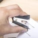 A person's hand using a Universal Black Jaw Style Staple Remover to remove a staple.