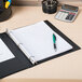 A black Avery Economy binder with pen and calculator on a desk.