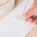 A hand putting a piece of Universal general purpose masking tape on a white envelope.