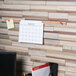 A brown cork bulletin bar on a wall with paper on it.