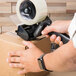 A hand using a Universal black handheld tape dispenser to seal a box.