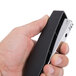 A hand holding a black and silver Universal full strip stapler.