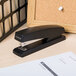 A black Universal full strip stapler on a table.