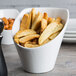 A close-up of a Tuxton TuxTrendz bright white china bowl filled with french fries.