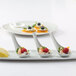 A white tray with three Tuxton bright white oval tasting spoons filled with fruit.