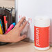 A hand using a Universal Pop-Up Dry Erase Cleaning Wet Wipe to clean a whiteboard.
