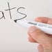 A person using a black Universal chisel tip dry erase marker to write the word "cats" on a white board.