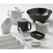 A white surface with a variety of white dishes and a white Tuxton pepper shaker.