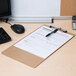A brown Universal hardboard clipboard holding a form with a pen on a wood desk.