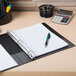 An Avery blue durable non-view binder with 1" slant rings on a desk with a pen and calculator.