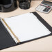 A white binder with Avery Write & Erase dividers on a table with a calculator.