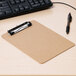 A brown Universal low-profile clipboard on a desk with a pen.