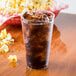 A Fineline clear hard plastic tumbler with soda and ice on a table with popcorn.