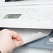 A hand inserting Avery white printable tabs into a printer.