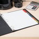 A binder with Avery Extra Wide Multi-Color Tab Dividers and white paper on a table with a calculator.