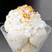 A glass bowl of ice cream topped with whipped cream and Regal Sweet Toasted Coconut Flakes.