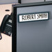 A white plastic cubicle nameplate with a grey frame on a grey box with the name Robert Smith on it.