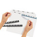 A hand holding Avery Index Maker folder dividers with clear label strip.