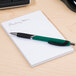 A green pen on a Universal white scratch pad.