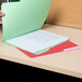 A person opening a green Universal file folder with papers inside.