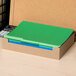 A box of Universal letter size file folders in assorted colors on a desk with a calculator and papers.