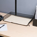 A white desk with a Universal black stackable mesh tray holding paper, a pen, and a mouse.