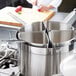 A group of Vollrath stainless steel pasta inserts with lids on top.