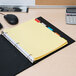 A binder with Avery 5-tab insertable dividers and yellow paper on a desk.
