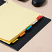 A yellow file folder with Avery multi-color tabs on it.