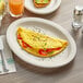 An Acopa narrow rim oval stoneware platter with an omelette and tomatoes on it.